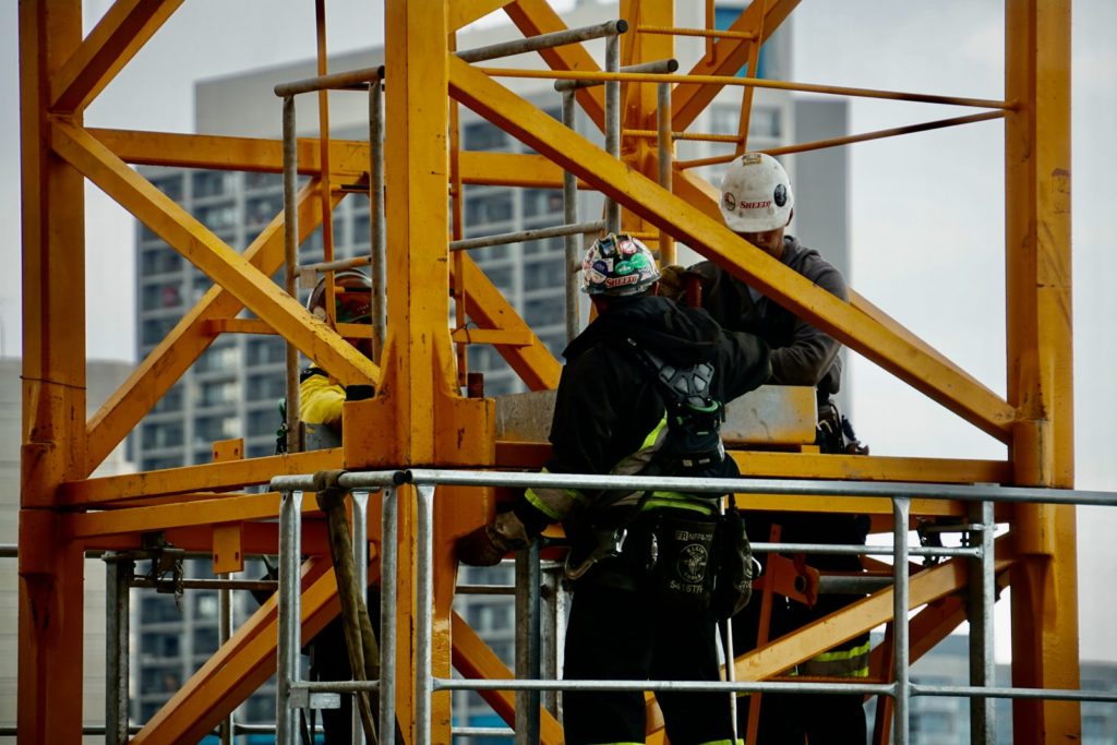 man in black jacket and helmet climbing orange ladder